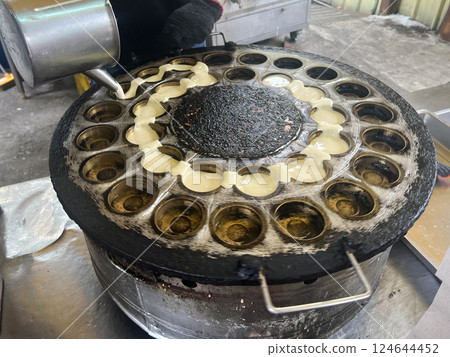 拍攝攤販熟練的將麵糊倒入模具中製作車輪餅 124644452