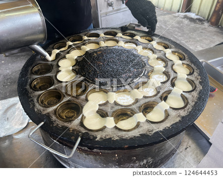 Filming the vendor skillfully pouring the batter into the mold to make wheel cakes Filming the vendor skillfully pouring the batter into the mold to make wheel cakes 124644453