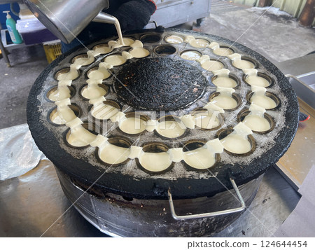 Filming the vendor skillfully pouring the batter into the mold to make wheel cakes Filming the vendor skillfully pouring the batter into the mold to make wheel cakes 124644454