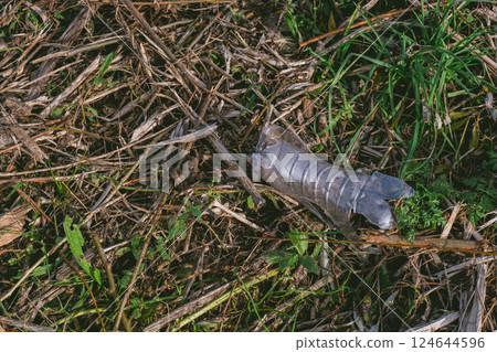 Bottle is laying on the ground in a field Bottle is laying on the ground in a field 124644596