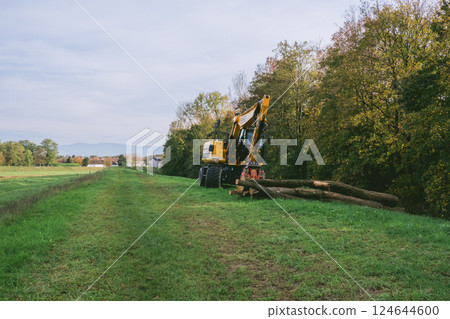 Tractor is in a field with trees in the background Tractor is in a field with trees in the background 124644600