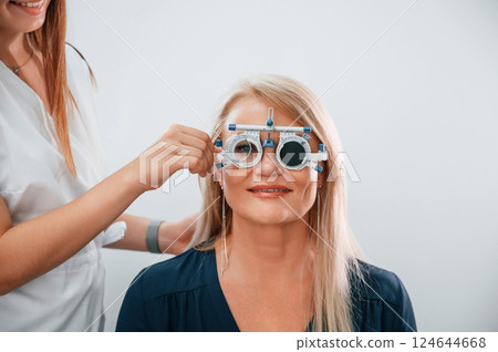 Wearing glasses. Woman's vision is tested by clinic worker that using special device 124644668