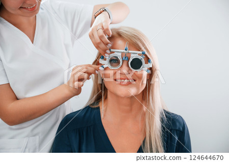 Wearing glasses. Woman's vision is tested by clinic worker that using special device 124644670