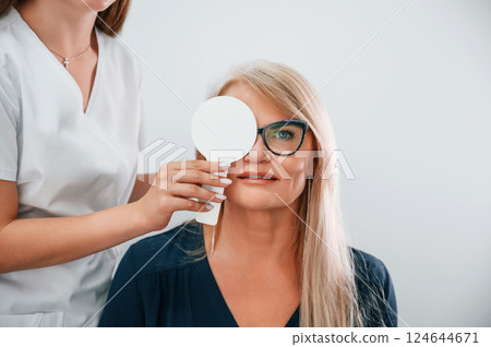 Covering the eye. Woman's vision is tested by clinic worker that using special device 124644671