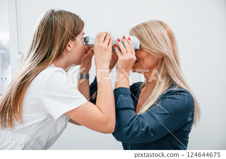 Woman's vision is tested by clinic worker that using special device Woman's vision is tested by clinic worker that using special device 124644675