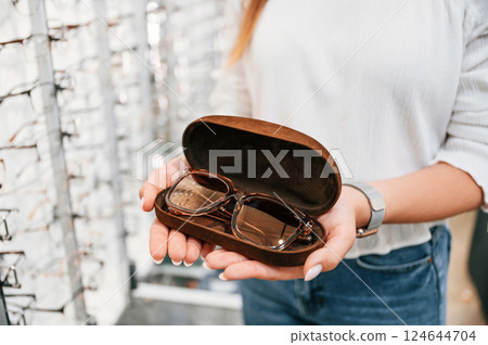 In brown colored case. Woman holding glasses in hands in the store. Close up view 124644704