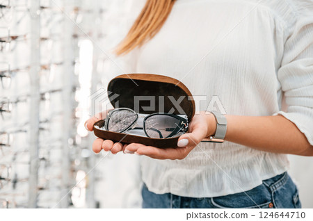 Holding case with glasses. Woman is in the store. Close up view 124644710