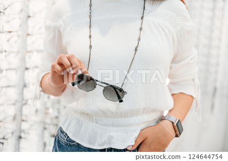 Woman holding glasses in hands in the store. Close up view Woman holding glasses in hands in the store. Close up view 124644754