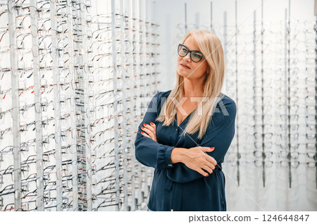 Standing with arms crossed. Woman in store trying new glasses 124644847
