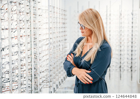 Standing with arms crossed. Woman in store trying new glasses 124644848