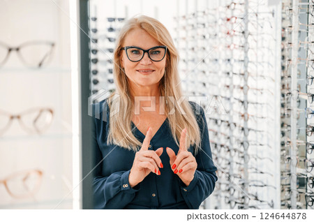 Looking at the camera. Woman in store trying new glasses Looking at the camera. Woman in store trying new glasses 124644878