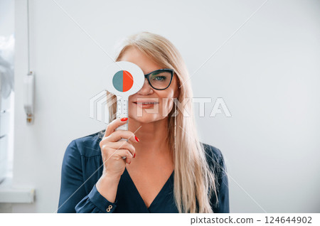 Woman sitting in the clinic and covering her eye. Testing vision 124644902