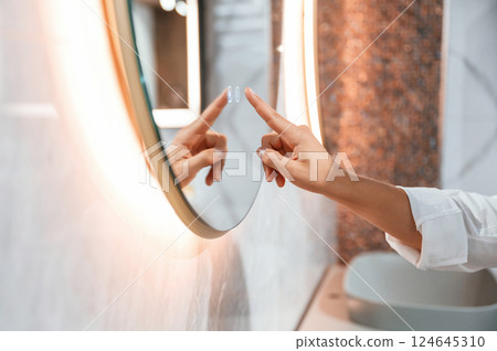 Using the mirror with touchscreen feature. Pretty young woman is in the store of goods for the home Using the mirror with touchscreen feature. Pretty young woman is in the store of goods for the home 124645310