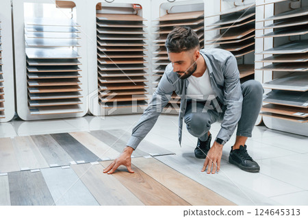 Looking for parquet. Stylish beautiful man is in the store of goods for the home Looking for parquet. Stylish beautiful man is in the store of goods for the home 124645313
