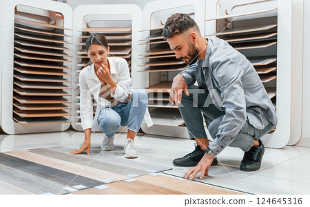 Choosing parquet. Woman and man is in the store of goods for the home Choosing parquet. Woman and man is in the store of goods for the home 124645316