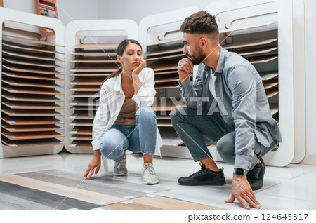 Choosing parquet. Woman and man is in the store of goods for the home Choosing parquet. Woman and man is in the store of goods for the home 124645317