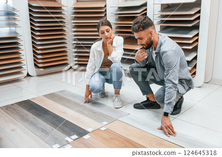 Choosing parquet. Woman and man is in the store of goods for the home Choosing parquet. Woman and man is in the store of goods for the home 124645318