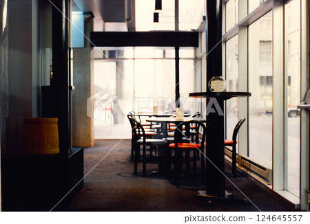Soft light and shadows of a modern cafe with blurred cars and buildings and black framed red seat chairs and tables Soft light and shadows of a modern cafe with blurred cars and buildings and black framed red seat chairs and tables 124645557
