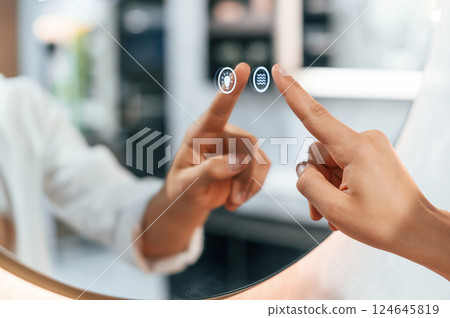 Using the mirror with touchscreen feature. Pretty young woman is in the store of goods for the home 124645819
