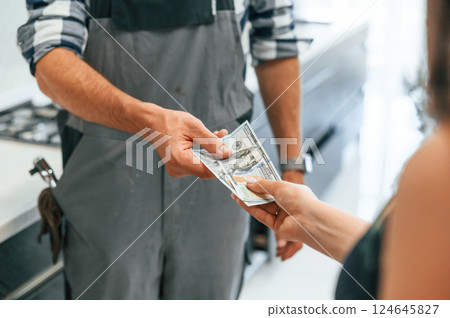 Close up view. Plumber receiving cash for the work he is done on the kitchen Close up view. Plumber receiving cash for the work he is done on the kitchen 124645827