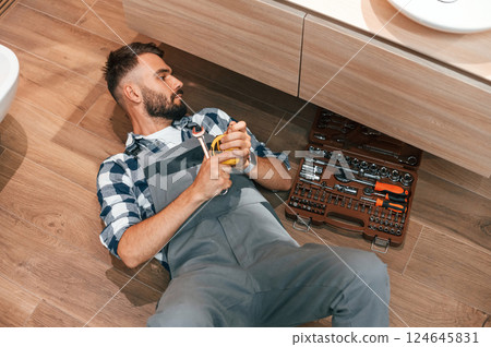 Plumber in uniform is indoors at home Plumber in uniform is indoors at home 124645831