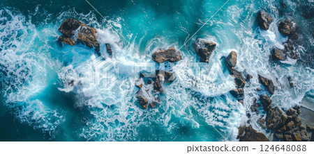 Aerial view of waves crashing on rocks, blue water, white foam, dynamic coastal design. 124648088