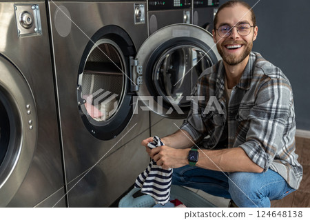 Man using qualified coin operated laundry machine in the public room to wash his cloths Man using qualified coin operated laundry machine in the public room to wash his cloths 124648138