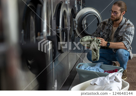 Man using qualified coin operated laundry machine in the public room to wash his cloths Man using qualified coin operated laundry machine in the public room to wash his cloths 124648144