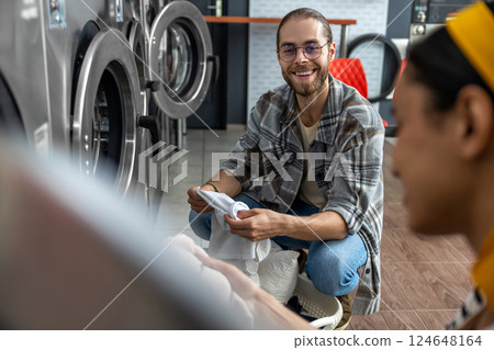 Man and woman together in commercial launderette using automatic washer and dryer Man and woman together in commercial launderette using automatic washer and dryer 124648164