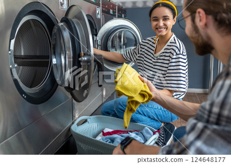 Woman and man using a self-service washing machine in public laundromat 124648177