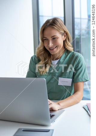 Female doctor sitting at table with laptop in workplace in hospital Female doctor sitting at table with laptop in workplace in hospital 124648196