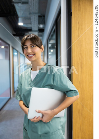 Female doctor standing in hospital corridor with laptop for digital case history Female doctor standing in hospital corridor with laptop for digital case history 124648206