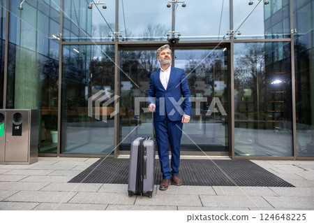 Mature businessman with a big suitcase arriving to destination Mature businessman with a big suitcase arriving to destination 124648225