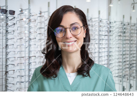 Pretty young dark-haired woman at the glasses stand in the optic shop 124648643
