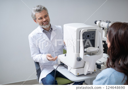 Gray haired man doctor examining woman patient eyes with professional technology 124648690