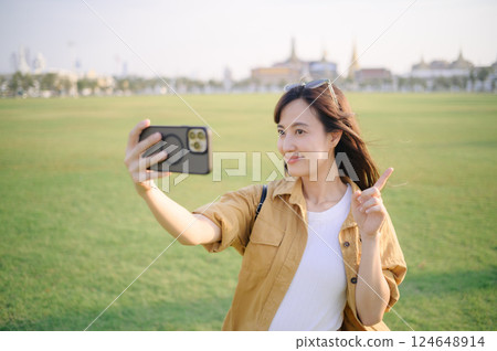 Traveler asian woman in her 30s making a livestream or selfie on smartphone. Immerse yourself in the religious heart of Bangkok with her Thailand adventure. Traveler asian woman in her 30s making a livestream or selfie on smartphone. Immerse yourself in the religious heart of Bangkok with her Thailand adventure. 124648914