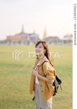 A Traveler Asian woman in her 30s exploring Wat Pra Kaew. From stunning architecture to friendly locals, she cherishes every moment, capturing it all in her heart and camera for years to come. 124648921