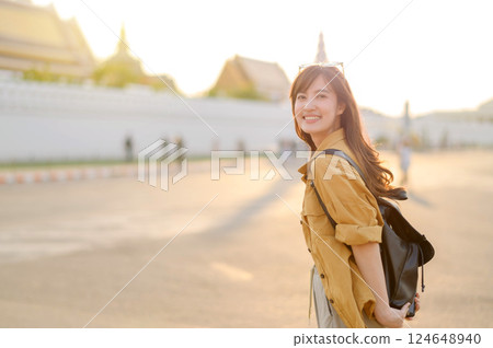 Traveler asian woman in her 30s stands bathed in the golden glow of sunset, embracing the freedom of exploration. on summer holiday weekend vacation trip in Bangkok, Thailand 124648940