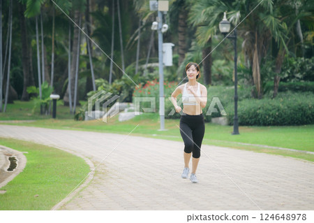 asian woman jogger running in green nature public park. 124648978