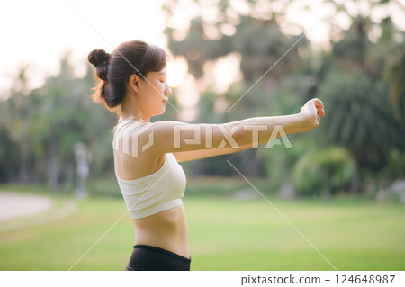 Sportswoman. Fit young Asian woman with sportswear stretching muscle in park before running and enjoying healthy outdoor. Fitness runner girl in public park. Wellness being concept 124648987