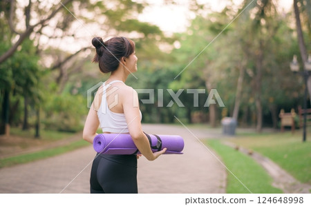 back of fitness yoga woman walking in the park with yoga mat 124648998
