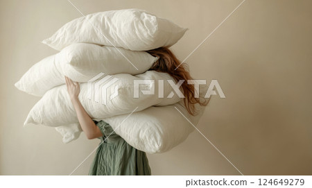 Woman Carrying a Stack of Pillows in Minimalist Setting 124649279