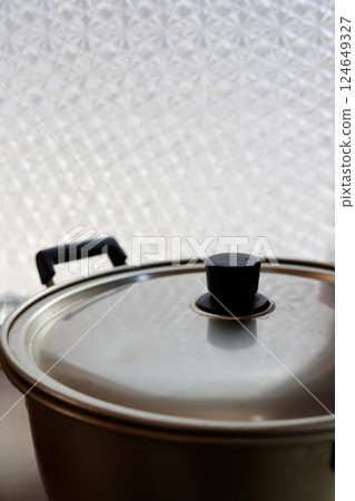 An old aluminum pot with a lid for a gas stove on a window sill 124649327