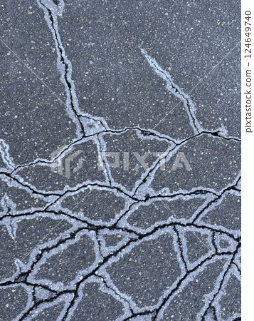 Cracked asphalt. Ice crystals and salt on the edges of the cracks. Cracked asphalt. Ice crystals and salt on the edges of the cracks. 124649740