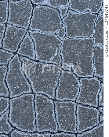 Cracked asphalt. Ice crystals and salt on the edges of the cracks. 124649742
