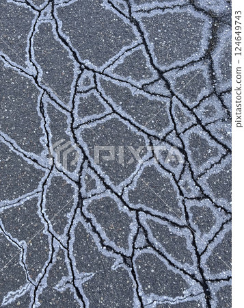 Cracked asphalt. Ice crystals and salt on the edges of the cracks. 124649743