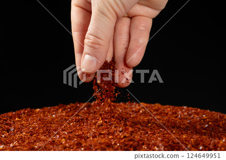 Hand pouring dried ground red hot chili peppers, natural seasoning, close-up Hand pouring dried ground red hot chili peppers, natural seasoning, close-up 124649951