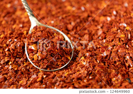 Crushed red hot chili pepper natural seasoning in a spoon Crushed red hot chili pepper natural seasoning in a spoon 124649960