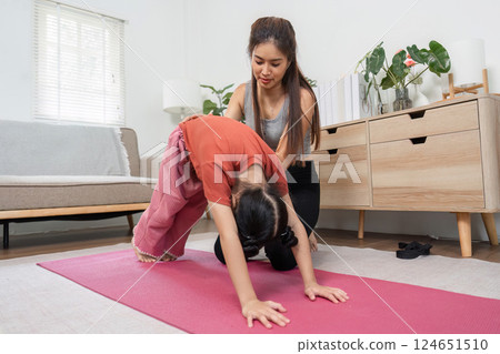 Yoga and Personal Growth. A child learns to execute the downward dog pose with guidance from a yoga teacher. 124651510