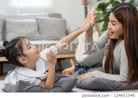 Joyful Moments and High-Fives. A mother shares a playful high-five with her daughter after a fun game. 124651546